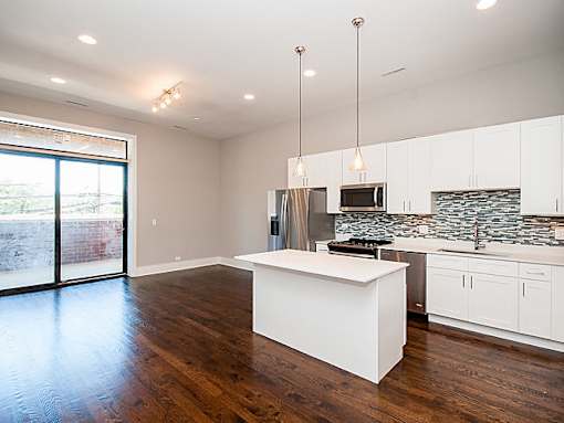 A modern kitchen with a white island and wooden floors.