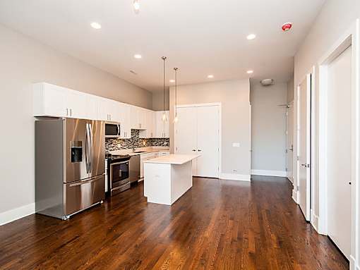 A kitchen with a refrigerator, microwave, and oven.