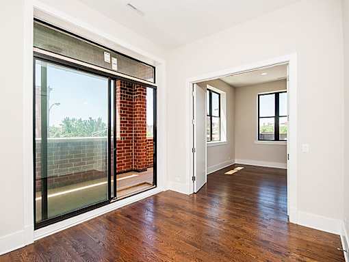 A room with a glass door and wooden floors.