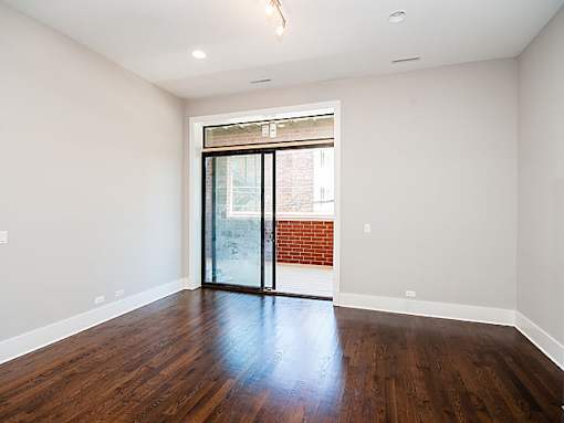 A room with a wooden floor and a glass door leading to a brick wall.