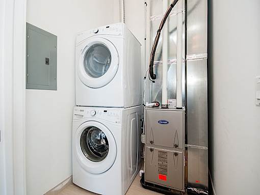 A stack of white front loading washing machines in a laundry room.