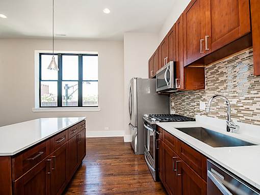 A kitchen with wooden cabinets and a stainless steel refrigerator.