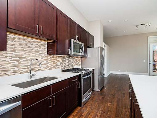 A kitchen with dark wood cabinets and a white counter top.