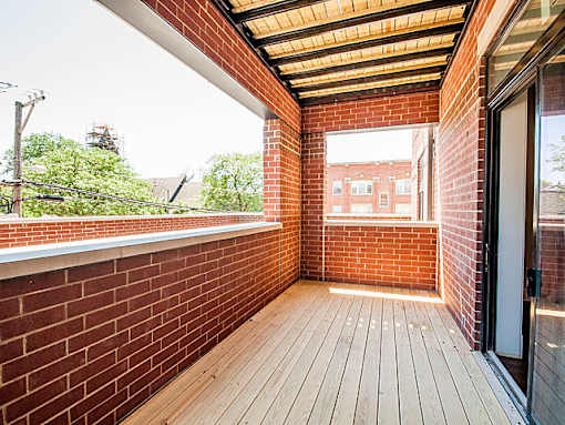 A balcony with wooden flooring and brick walls.
