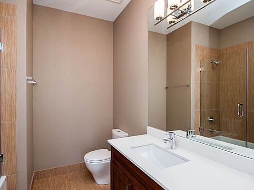 A bathroom with a toilet, sink, and mirror.