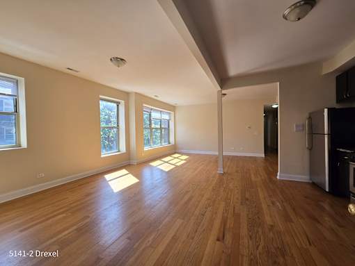 an empty living room with hard wood floors and windows
