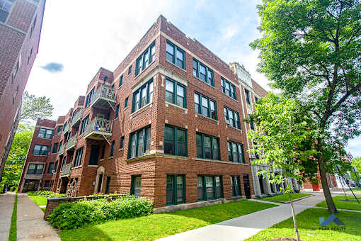 a red brick building with green grass and trees