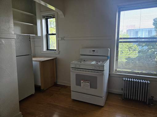 A white oven and stove in a kitchen with wood floors and white walls.