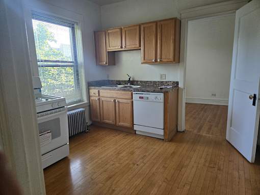 A kitchen with wooden floors and white appliances.