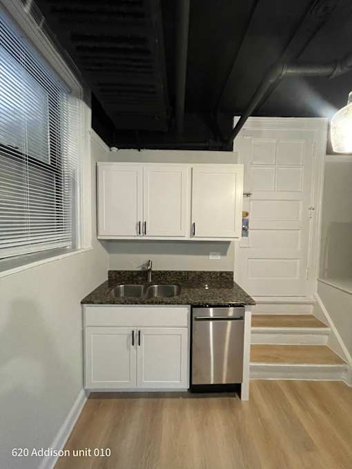 a small kitchen with white cabinets and a stainless steel sink