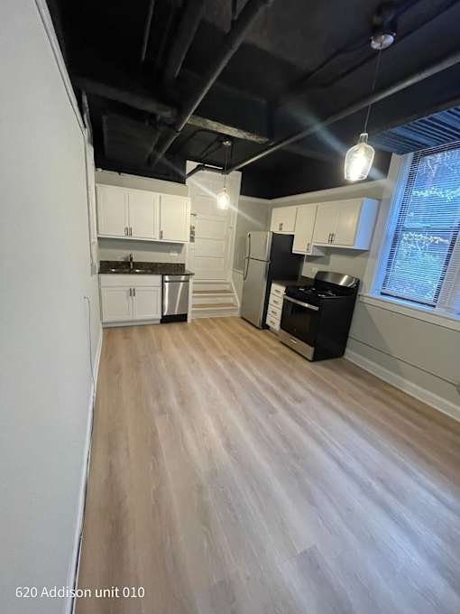 an empty kitchen with white cabinets and a black ceiling