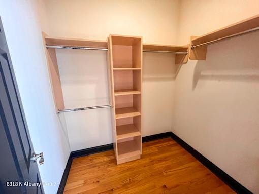 a walk in closet with shelves and a refrigerator