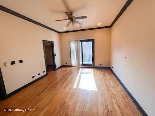 an empty living room with wooden floors and a ceiling fan