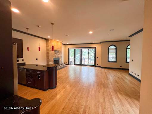 an open kitchen and living room with wood floors and a fireplace