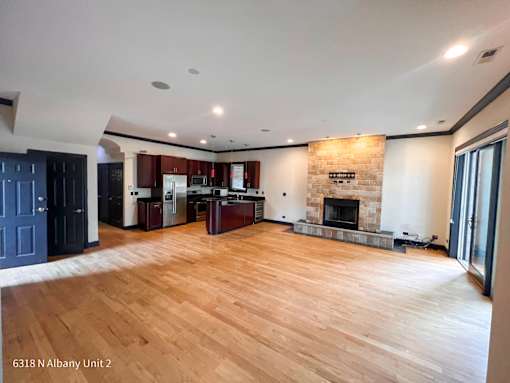 an empty living room with a fireplace and a kitchen