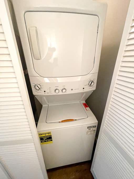 A white dryer and washer are sitting in a small space.