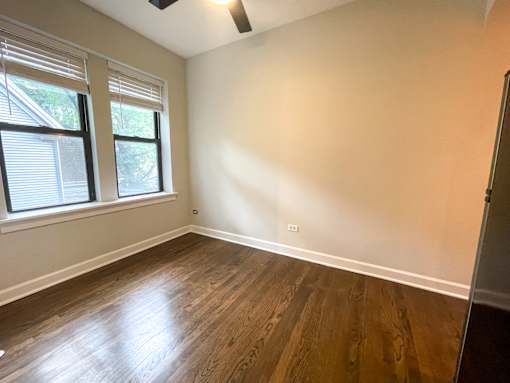 A room with wooden flooring and a window with blinds.