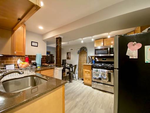 A kitchen with a black fridge and a stove top oven.