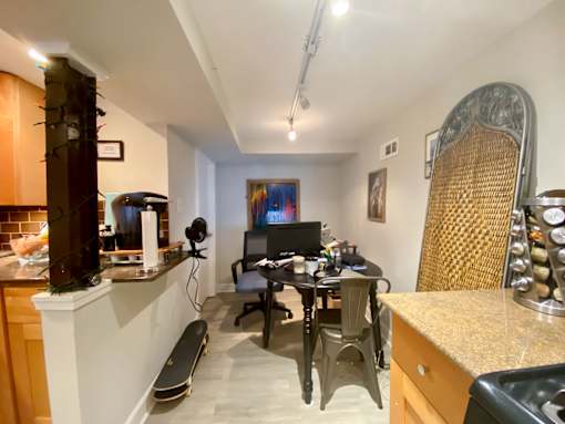 A room with a desk, chairs, and a skateboard.