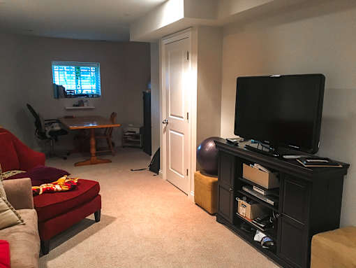 A living room with a red couch, a television, and a ball.