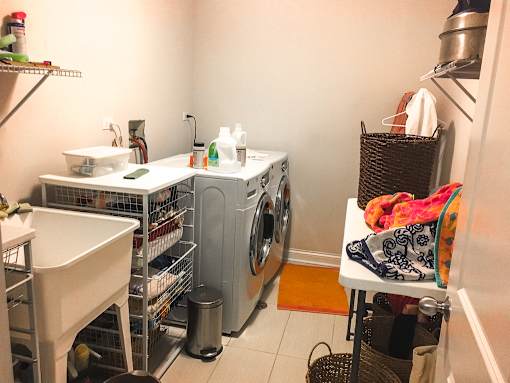 A laundry room with a washer and dryer, a sink, and a basket of clothes.