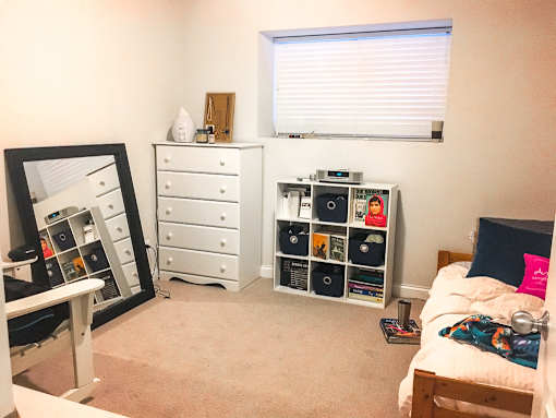 A bedroom with a bed, dresser, and a mirror.