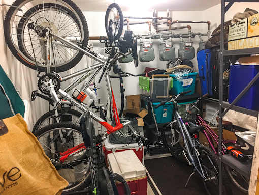 A bike repair shop with a bicycle hanging from the ceiling.