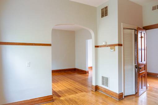A room with a wooden floor and a white wall with a brown trim.