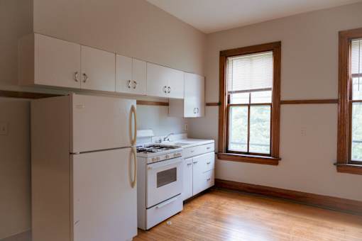 A white kitchen with a refrigerator, stove, and cabinets.