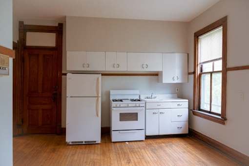 A kitchen with white appliances and wooden floors.