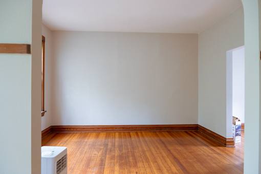 A room with a wooden floor and a white air conditioner unit.