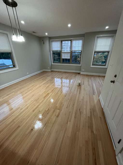 an empty living room with wooden floors and windows