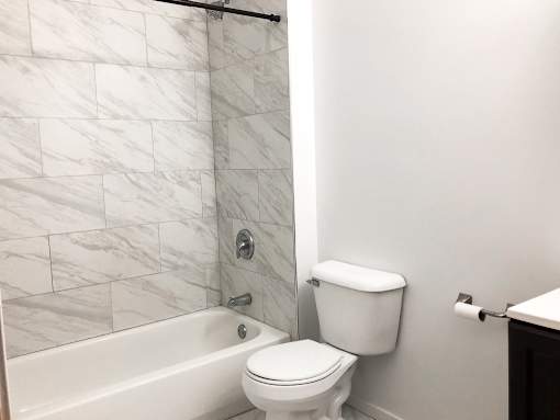 A white toilet sits next to a bathtub in a bathroom.