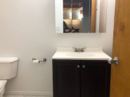 A bathroom with a white sink and a brown cabinet.
