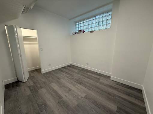 A room with a grey floor and a window with blinds.