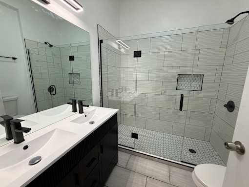 A bathroom with a walk in shower and double sinks.