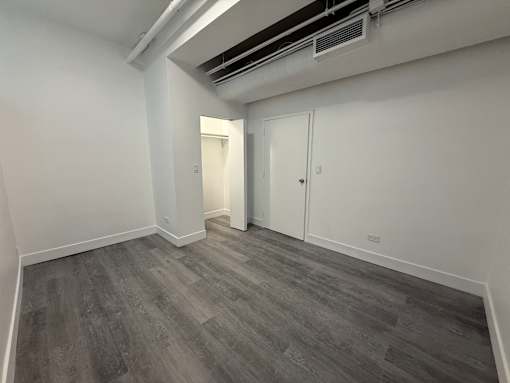 A room with grey flooring and white walls, featuring a door and a window.