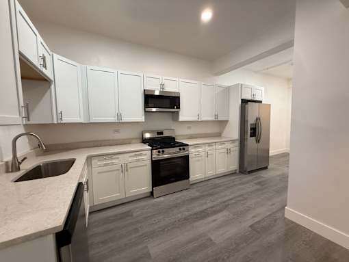 A kitchen with white cabinets and a grey floor.