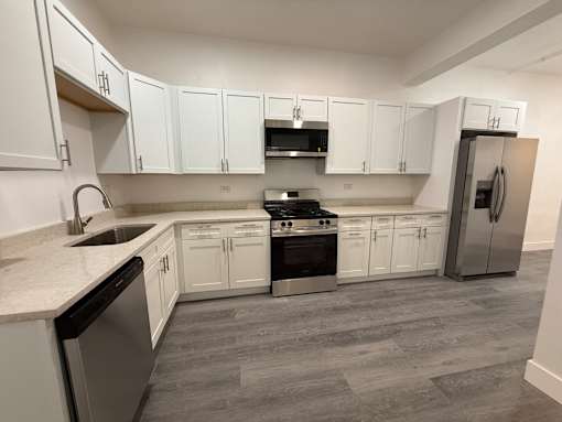 A kitchen with white cabinets and a stainless steel refrigerator.