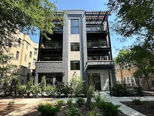 A modern building with a black and white facade is surrounded by greenery.