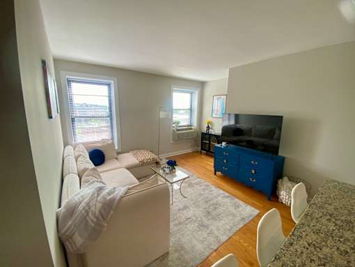 A living room with a white couch, a blue cabinet, and a grey rug.