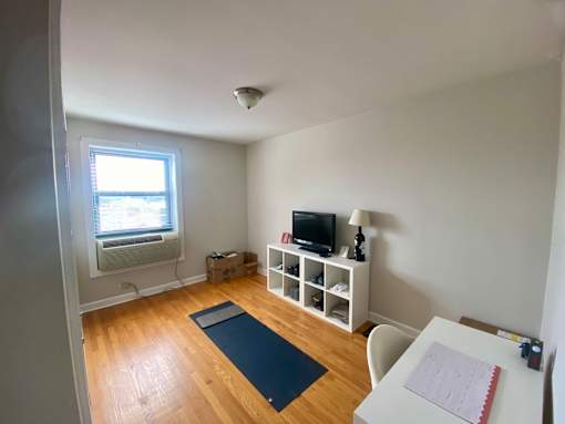A room with a desk, chair, and a yoga mat on the floor.