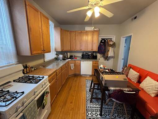 A kitchen with a stove, a table, and a couch.