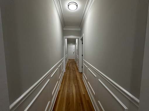 A long hallway with white walls and wood flooring.