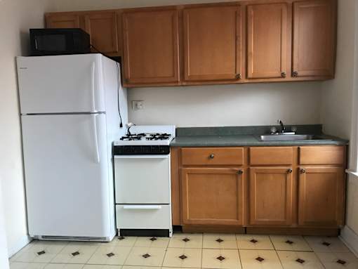 A kitchen with a white fridge, black microwave, and a white stove.