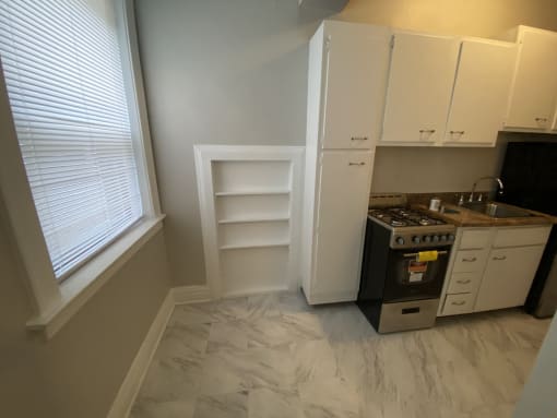 a small kitchen with white cabinets and a sink and a stove