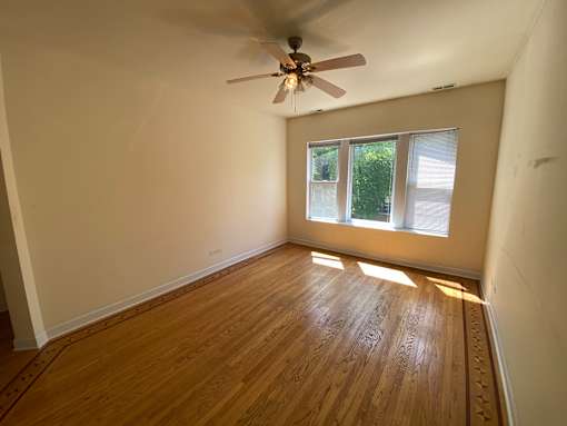 A room with a ceiling fan and wooden flooring.