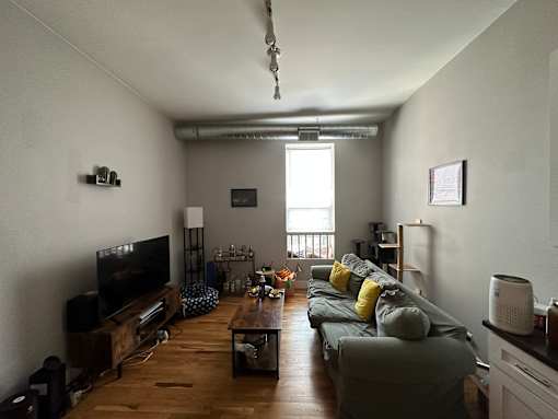 A living room with a grey couch and a wooden floor.