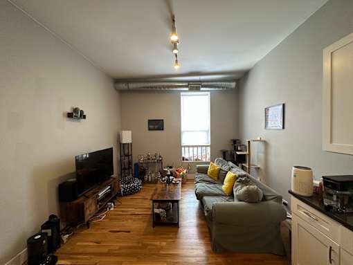 A living room with a grey couch and a wooden floor.
