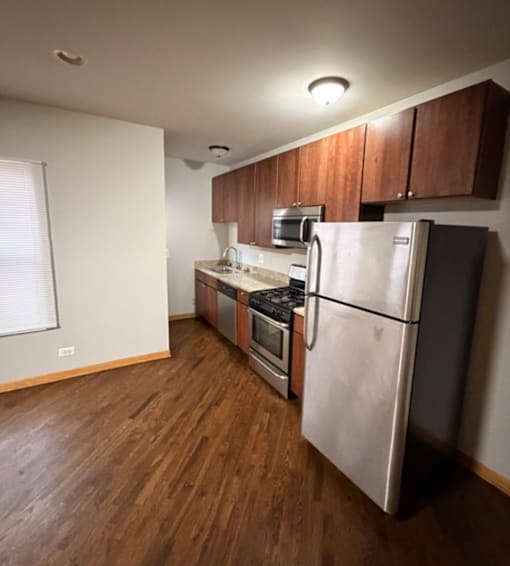 A kitchen with a refrigerator, oven, and microwave.